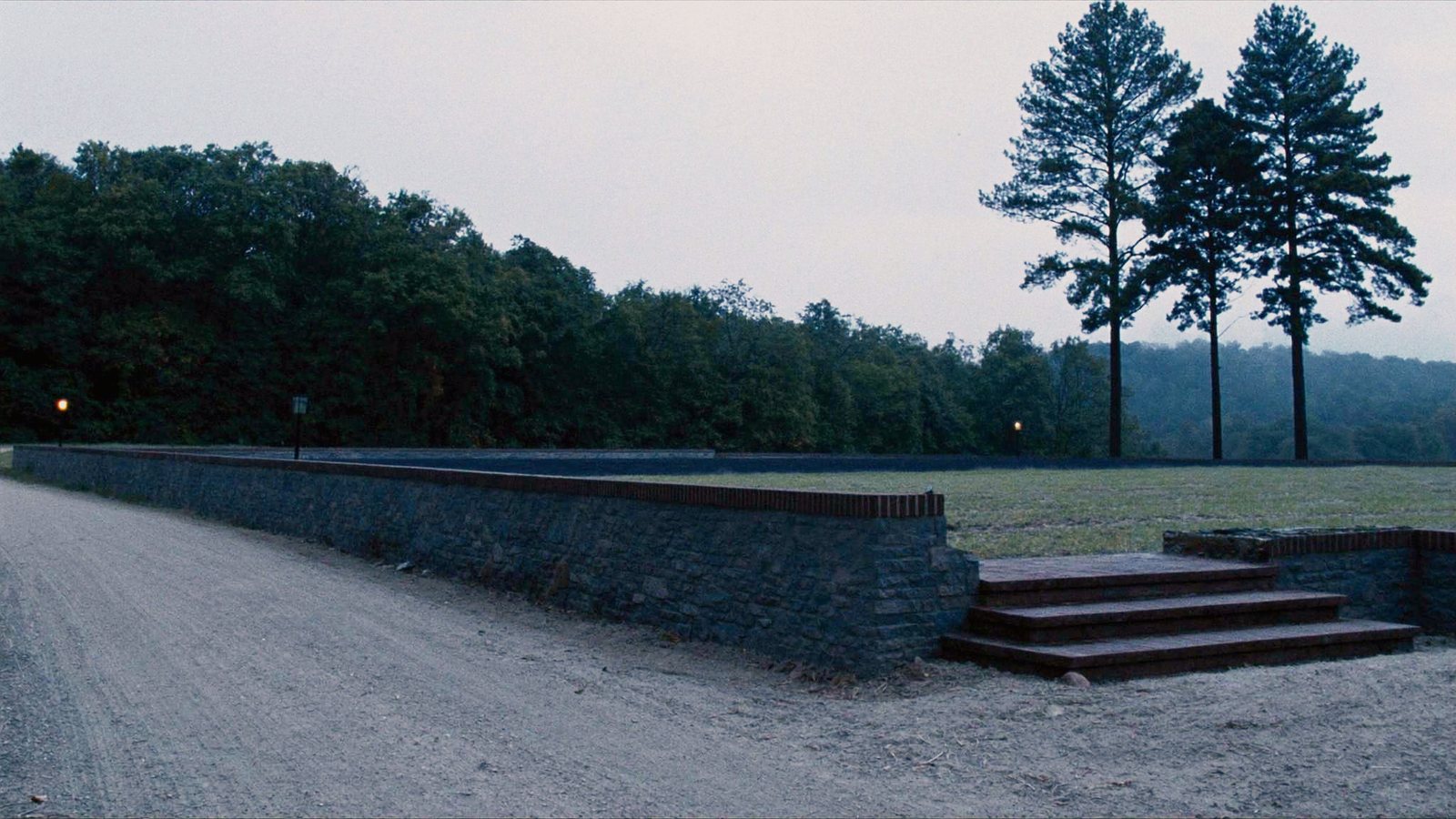 The finished lot: a long stone retaining wall with brick steps holding a level pad
